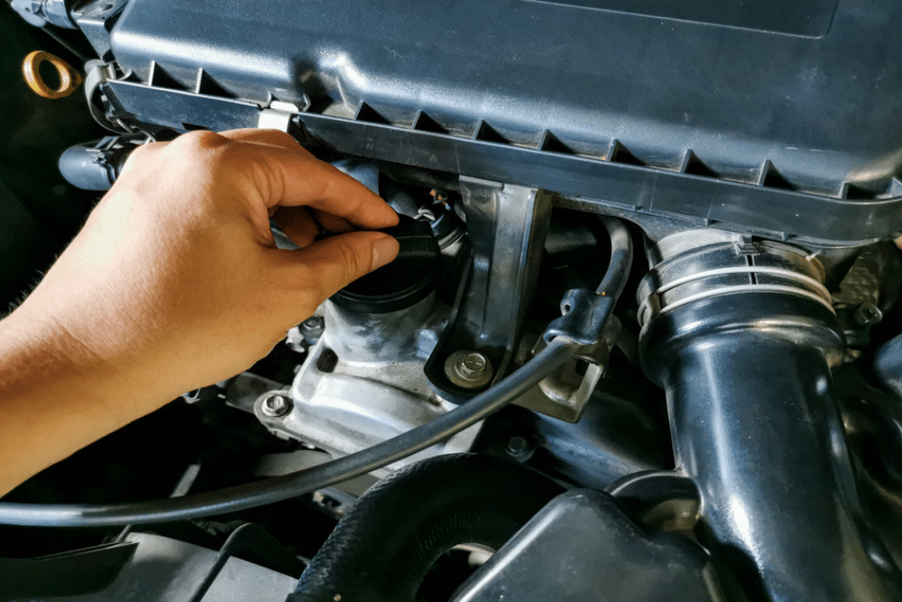 reliable car repair in Arcata, CA at North Bay Automotive. Mechanic’s hand unscrewing the oil cap on a car engine, highlighting preventative maintenance and proper vehicle care.