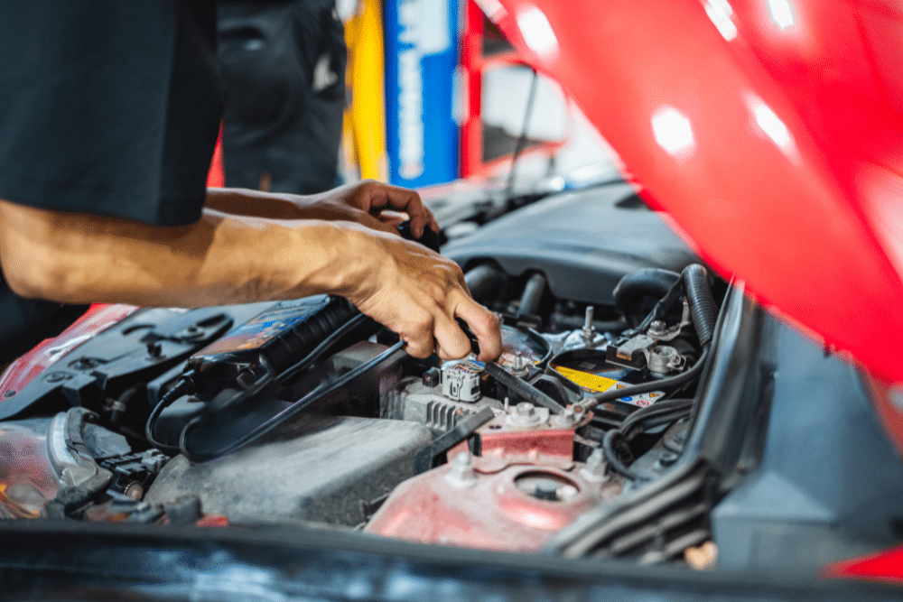 Car Maintenance in Arcata, CA at North Bay Automotive. A mechanic’s hands work on the engine of a car with the hood open, using tools to perform maintenance in a brightly lit auto repair shop.