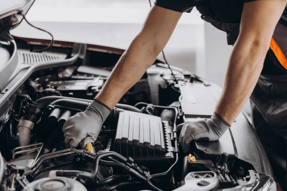 Vehicle Inspection in Arcata, CA at North Bay Automotive. A mechanic wearing gloves works under the hood of a car, inspecting engine components during a repair.